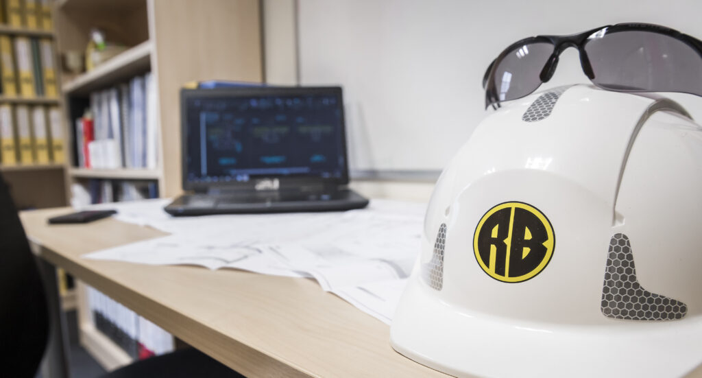 Safety glasses placed on top of a Roger Bullivant hard hat